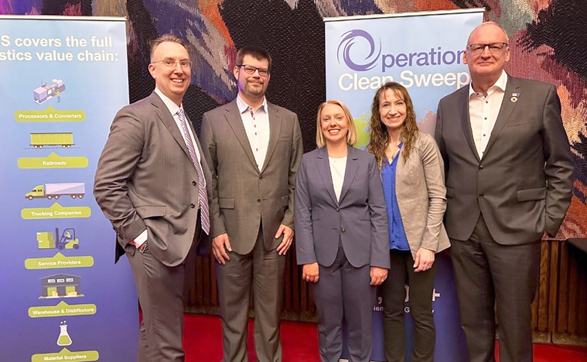 5 people including Benny Mermans and Steven Prusak in front of banners showing the Operation Clean Sweep (Photo)