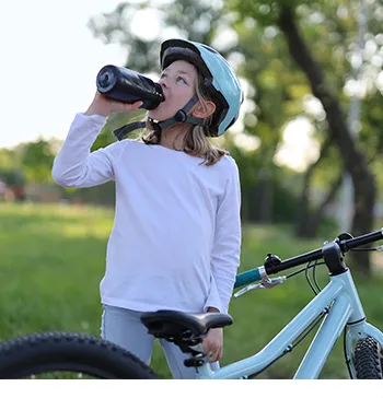 A girl making a break from riding her bike to drink from a water bottle (Photo)