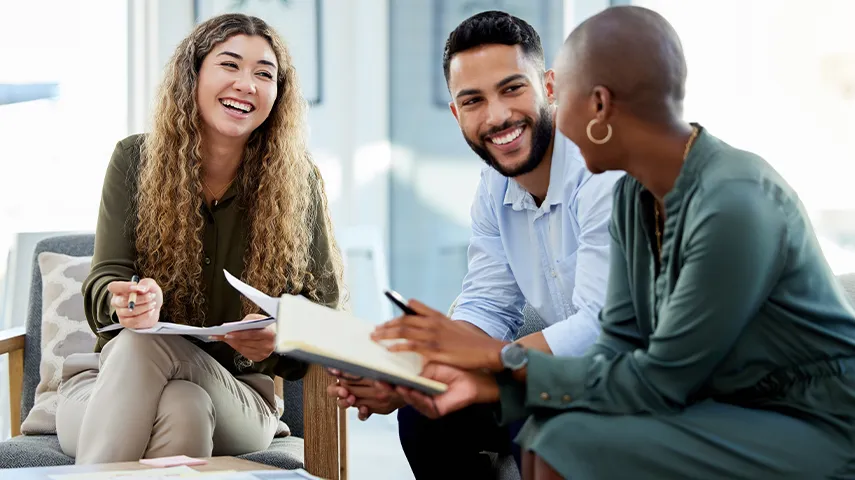 Three people sitting together talking to each other with smiles on their faces (Photo)