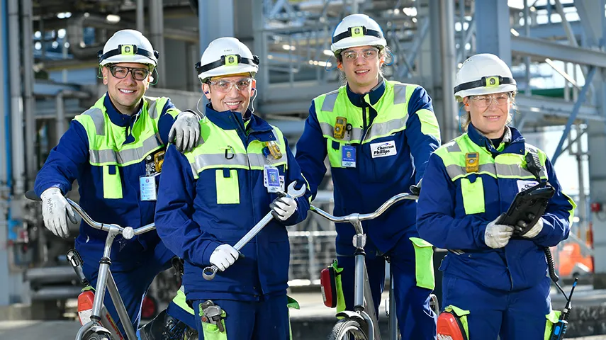 four employees in working clothes and safety gear holding different tools (Photo)