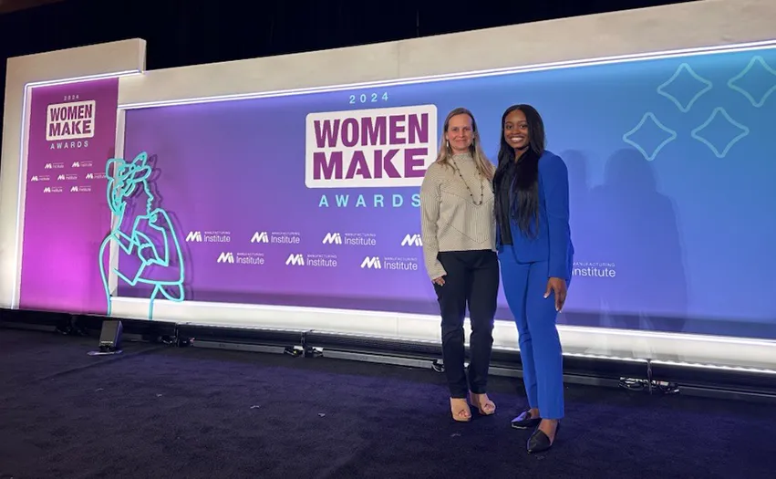 Two woman standing in front of a themed wall for the Woman Make Awards (Photo)