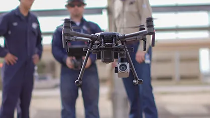 three people standing behind a flying drone (Photo)