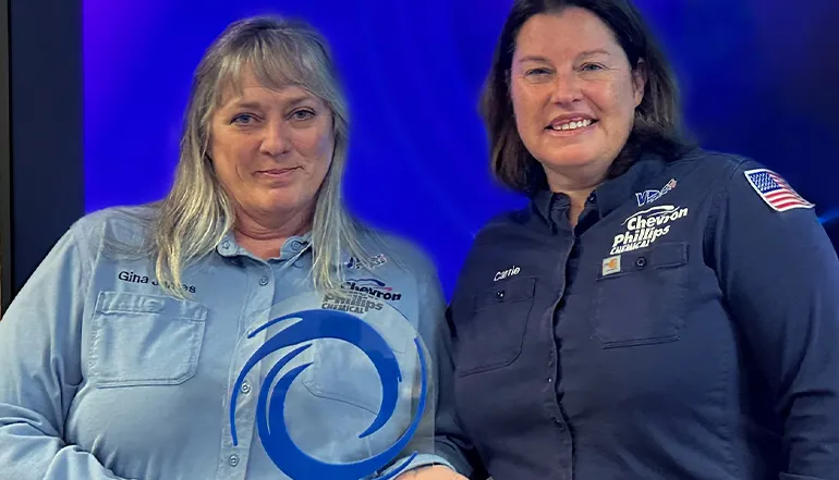 This is an image of two individuals posing for a photo, presumably at some sort of event. Both women are wearing shirts with "Chevron Phillips Chemical" on it and smiling into the camera.