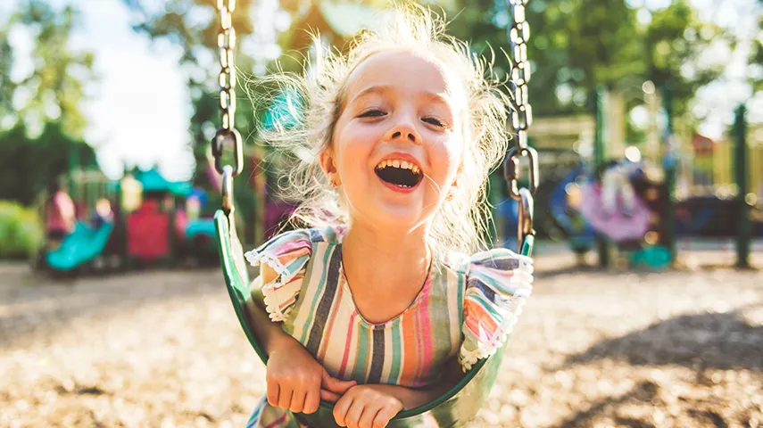 A happily laughing girl learning on a swing on a sunny day (Photo)