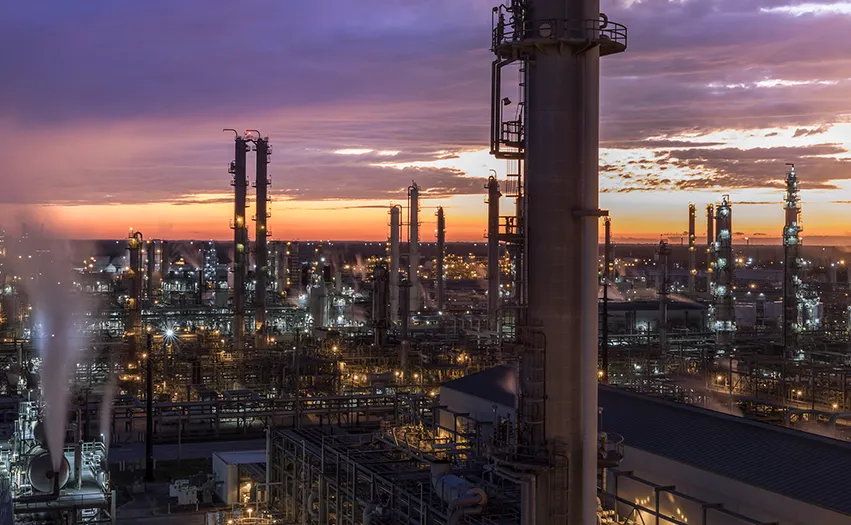 An industrial site at dawn with many pipes and lights (Photo)