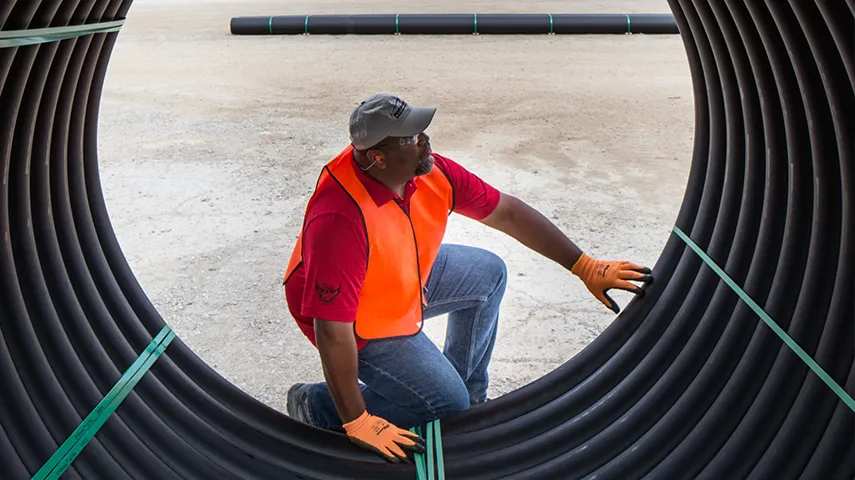 A man with a safety vest and gloves inspecting a big pipe (Photo)