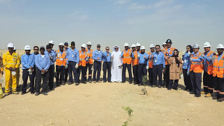 A bigger group of emloyees, mainly in work wear on a very sunny day in Qatar (Photo)