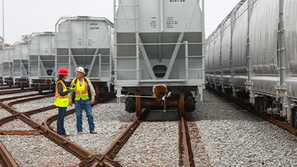Two workers discussing on a rail yard with many railway cars. (Photo)