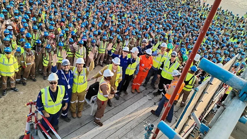 A big crowd of people in workwear waving to the camera photographed slightly from above (Photo)